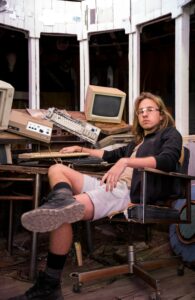 A man sitting in a chair in front of a computer. Photo by David Behar on Unsplash