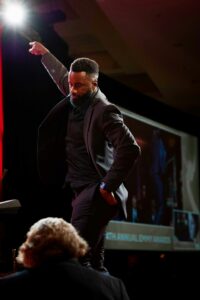 A black man dancing on stage, celebrating ceremony. Photo by De'von wellesley on Unsplash